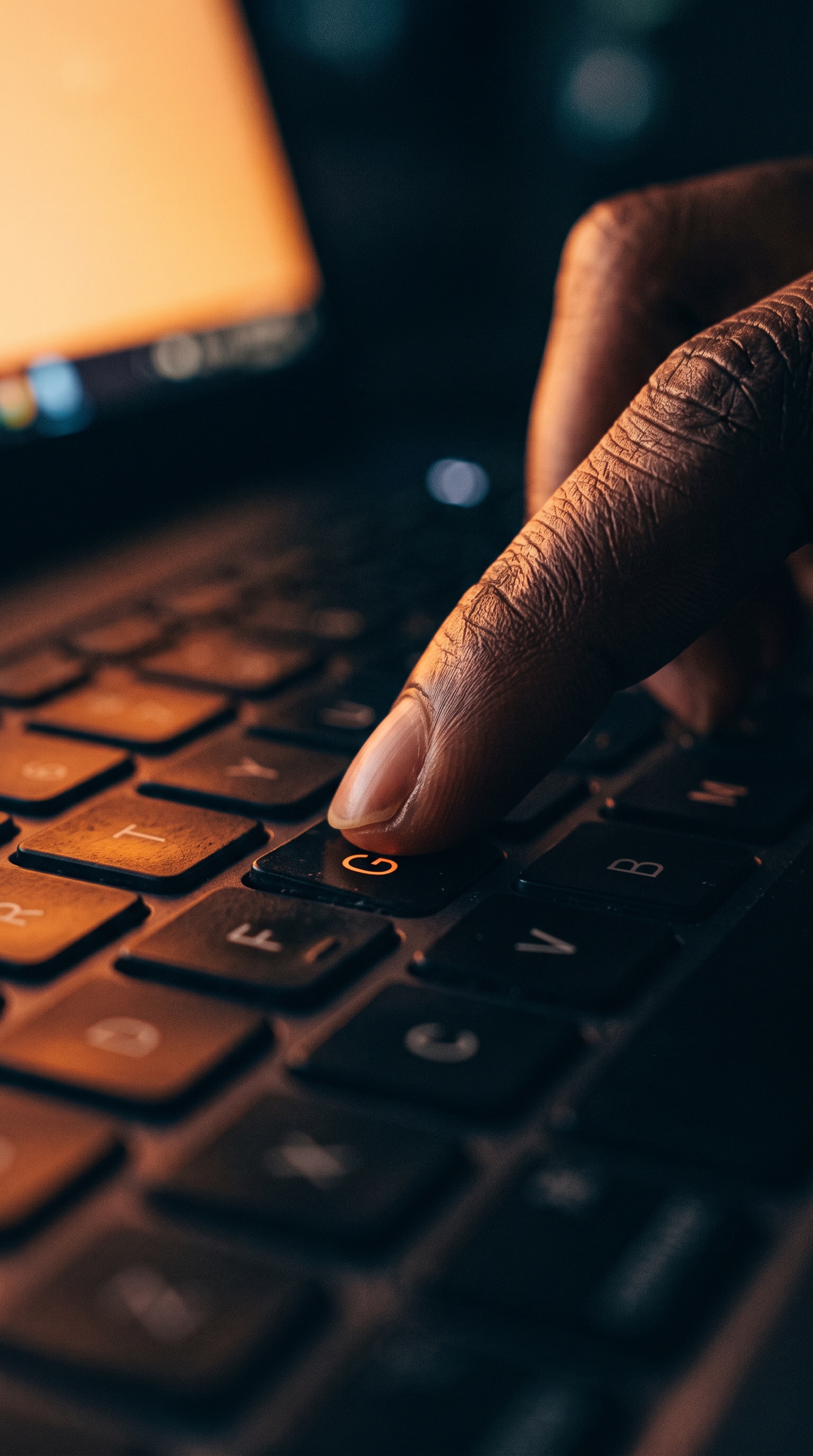 Close macro of a fingertip on a glowing keyboard key